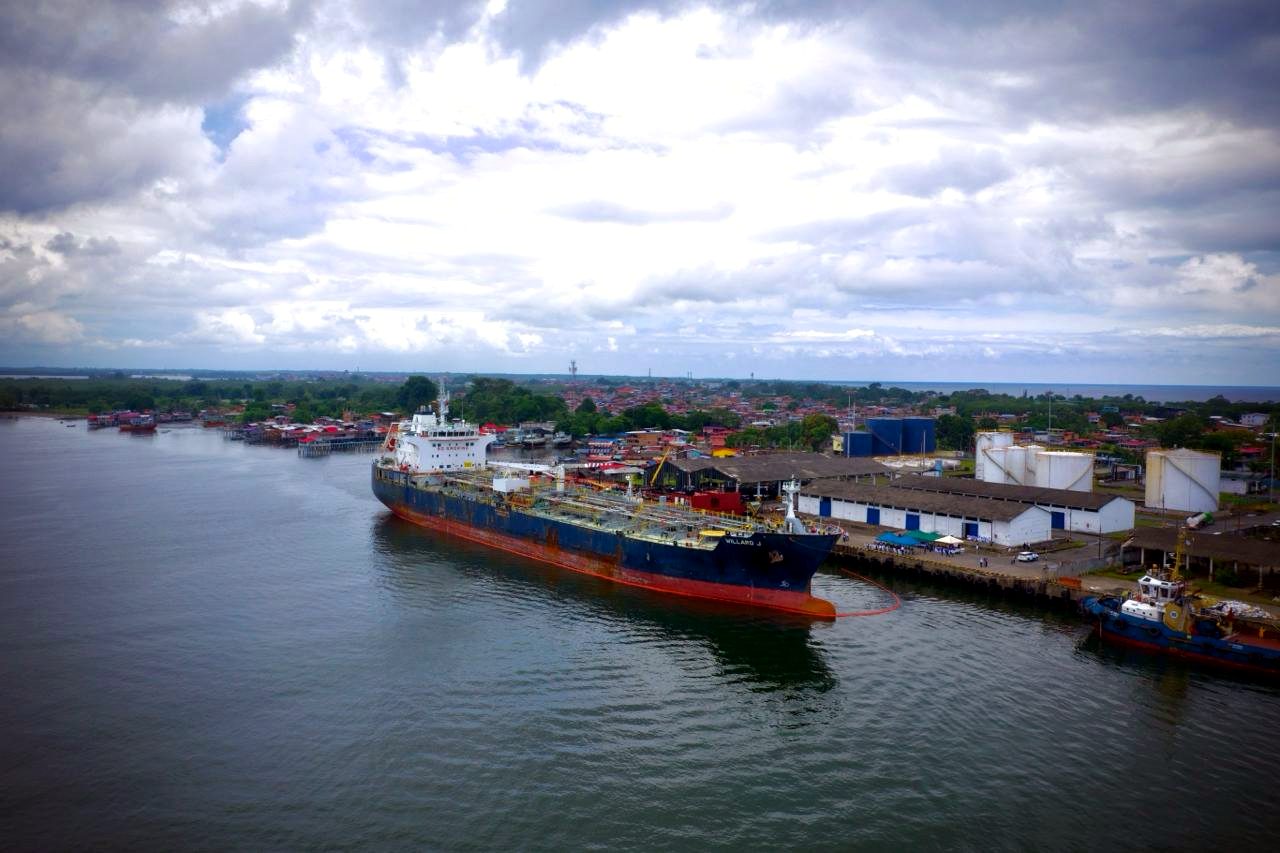 Buque-tanque atracado en el puerto de Tumaco sobre la bahía del Pacífico, con tanques de almacenamiento al fondo